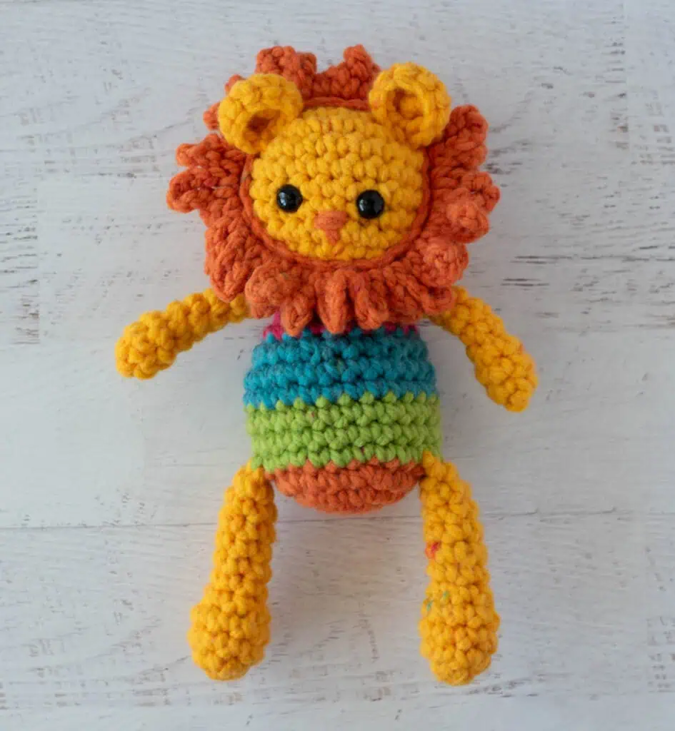 A yellow and orange rochet lion with a rainbow striped body