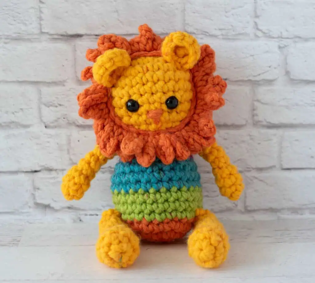 A yellow and orange rochet lion with a rainbow striped body