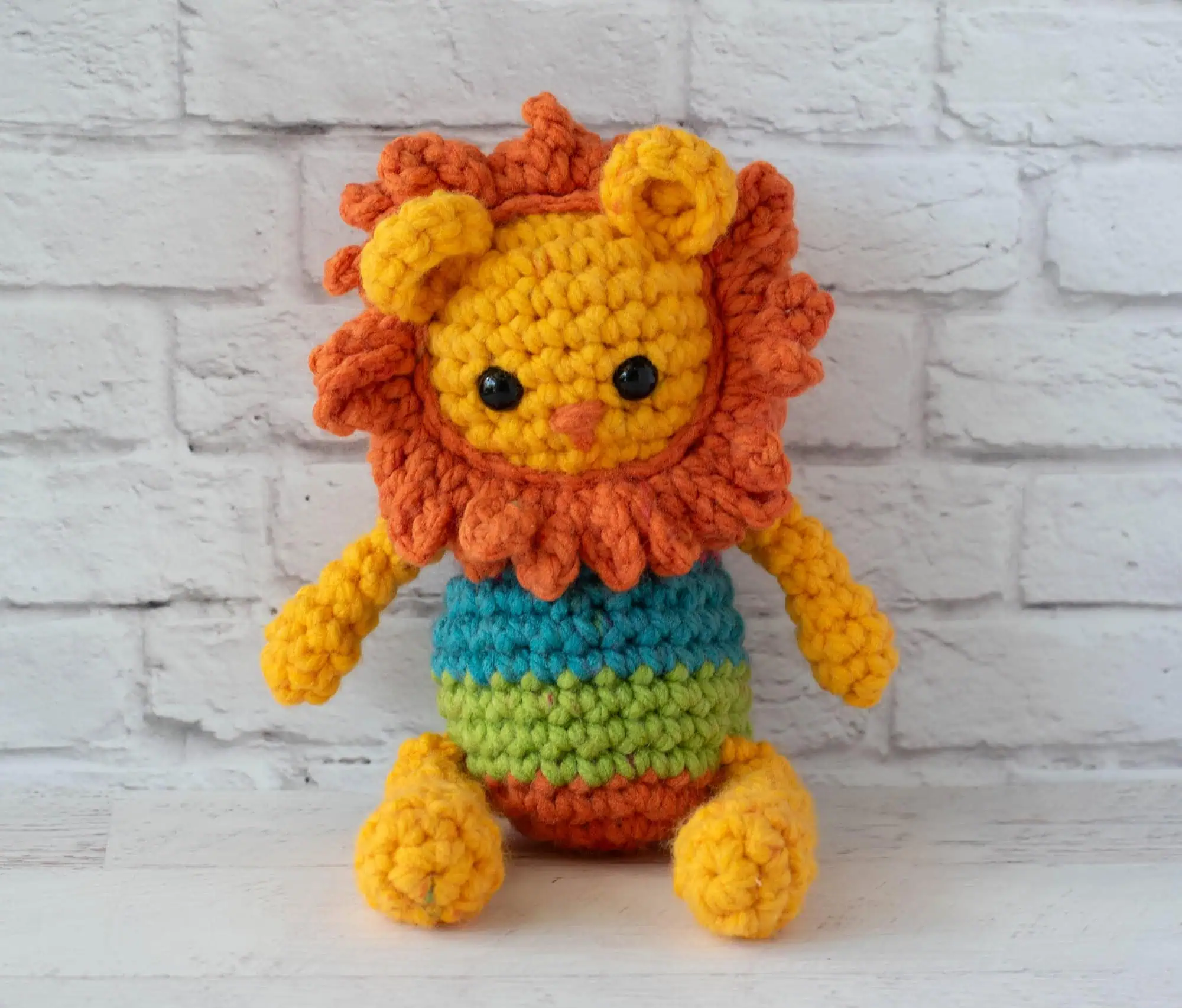 A yellow and orange rochet lion with a rainbow striped body