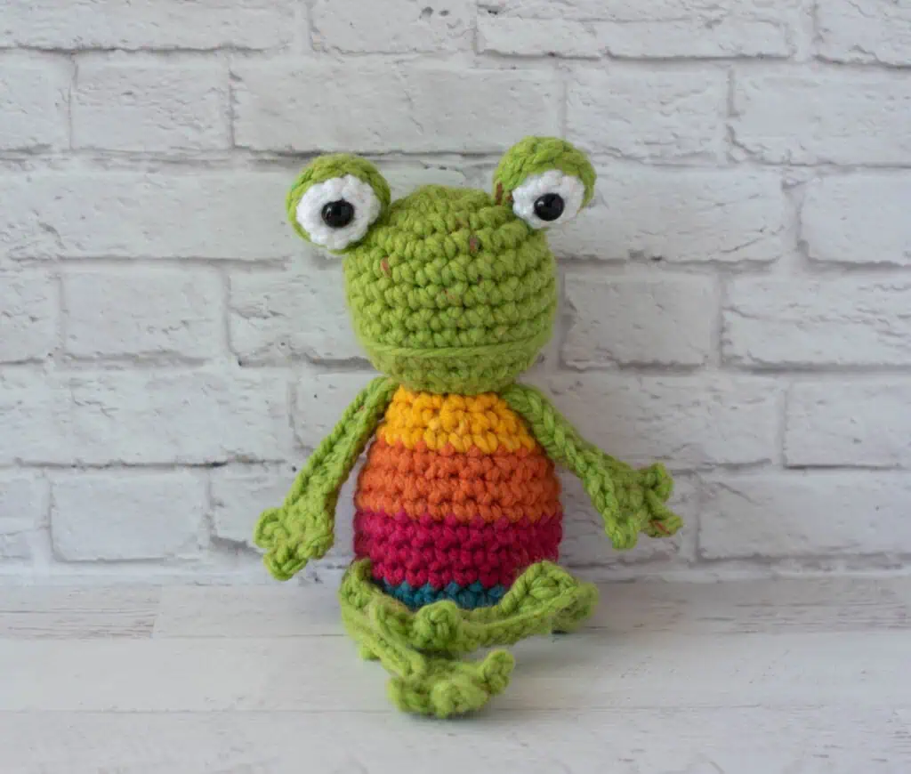 Crochet green frog with yellow, orange, red and blue striped body