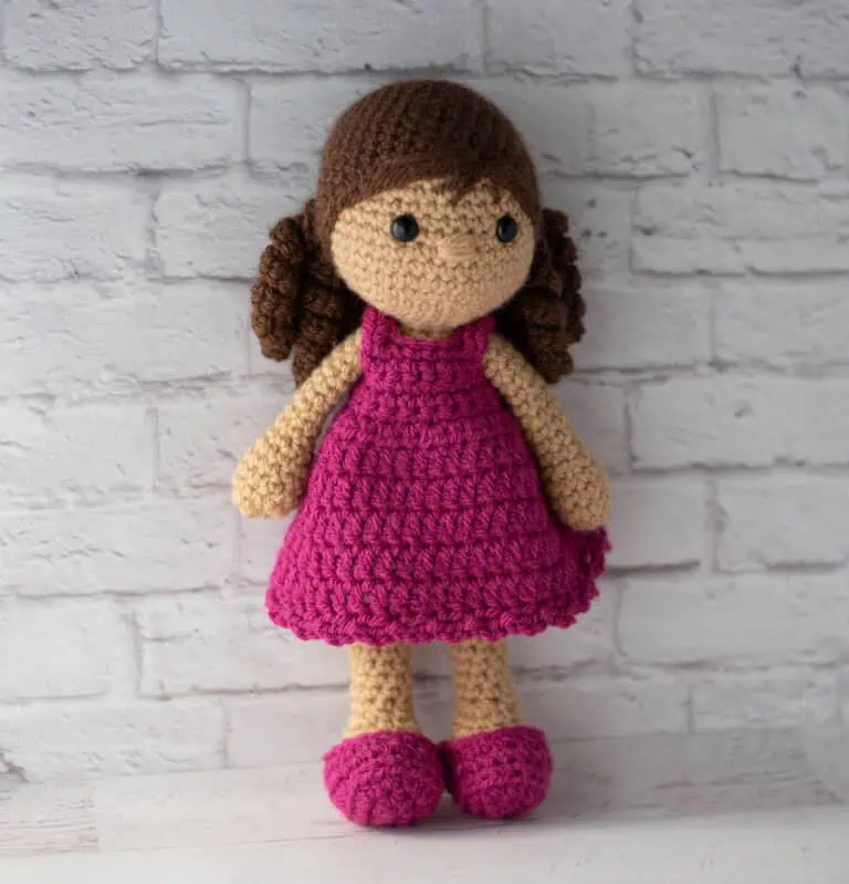 Crochet doll with brown hair and pink dress and shoes