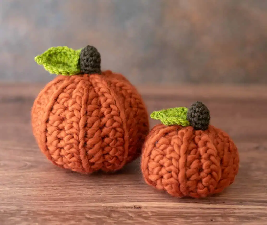 2 Orange crochet pumpkins with green leaves and dark brown stem