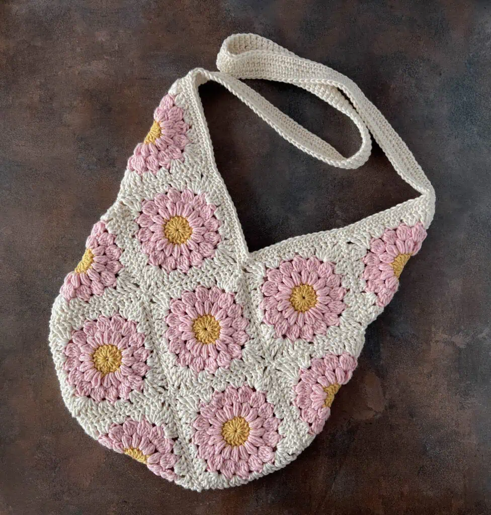 Pink and yellow flower crochet granny square bag on brown background