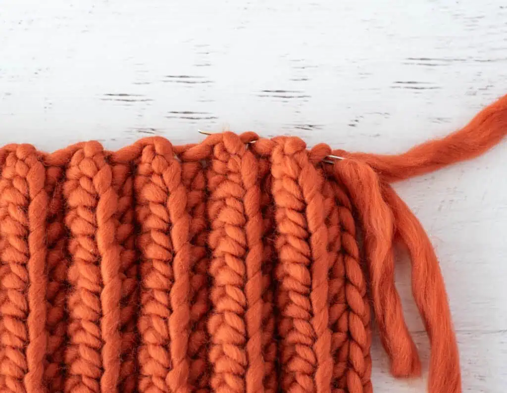 Image of orange crochet rectangle in the process of being sewn into a pumpkin