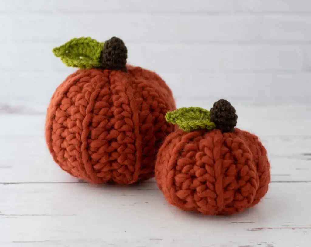 Orange crochet pumpkins with green leaves and dark brown stem