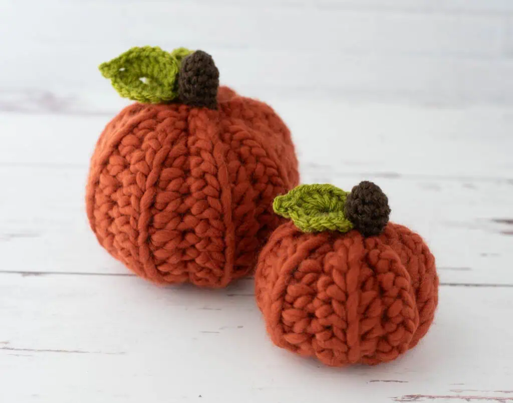 2 Orange crochet pumpkins with green leaves and dark brown stem